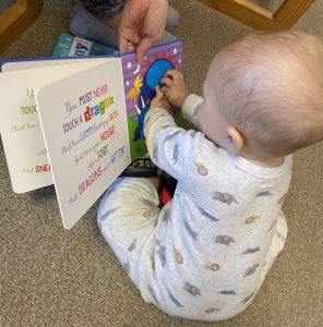 Decorative image of baby looking at board book