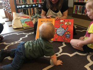 Decorative image of a baby being read a board book
