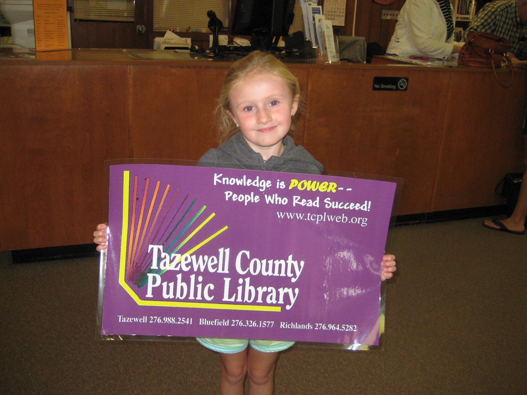 Decorative image of girl holding up a large library card